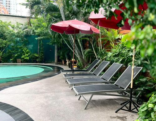 a row of chairs with umbrellas next to a pool at Manhattan Hotel Bangkok in Bangkok
