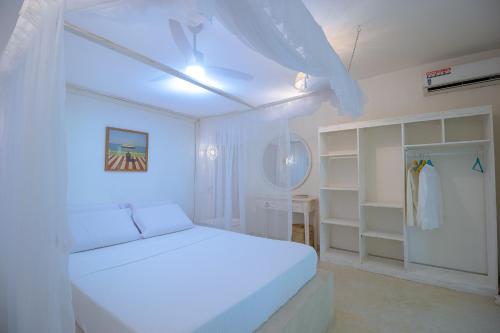 a white bedroom with a bed and a closet at Villa Zuri at Papa Remo in Watamu