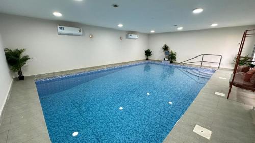 a large swimming pool in a building with a blue pool at Al Hawli pool gathering in Salalah