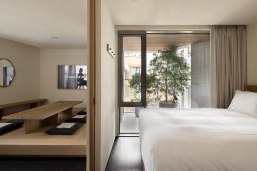 a bedroom with a bed and a table and a window at Long Weekend Haus in Seoul