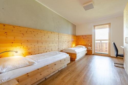 two beds in a room with a wooden wall at Ferienwohnung La-Wurm mit privatem Whirlpool in Hart im Zillertal