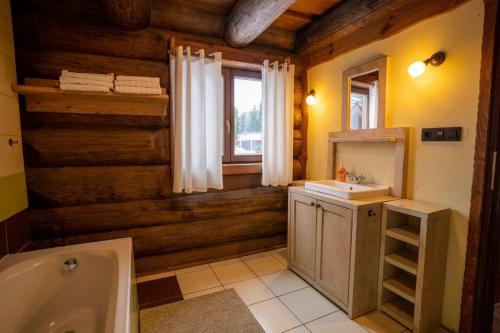 a bathroom with wooden walls and a tub and a sink at Chalet Vancouver in Donovaly