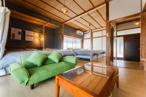 a living room with a green couch and two beds at Azure Kawatana in Mitsugoe