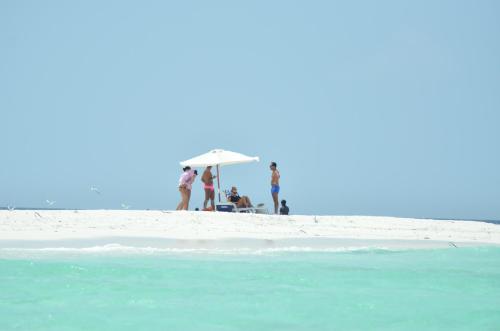 a group of people standing on a beach under an umbrella at Olhumathi View Inn in Ukulhas