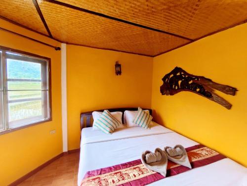 a bedroom with yellow walls and a bed with shoes on it at The Countryside Pai in Pai