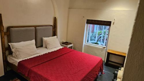 a bedroom with a bed with a red blanket and a window at Le Jardin Suffren LOFT in Jāmb