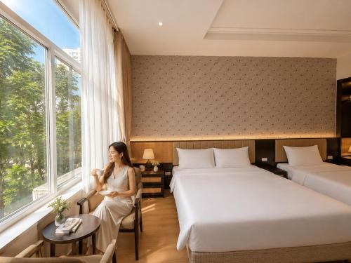 a woman sitting in a room with two beds at D'la Lento Hotel in Hanoi