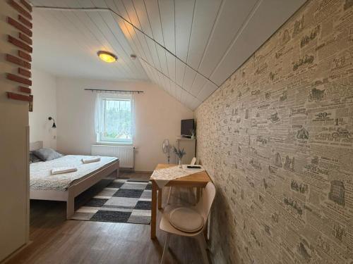 a bedroom with a bed and a table and a wall at Penzion V Hájku in Vřesina