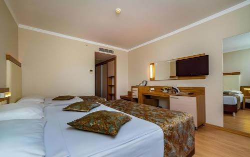 a hotel room with two beds and a television at Calimera Hane Garden Hotel in Side