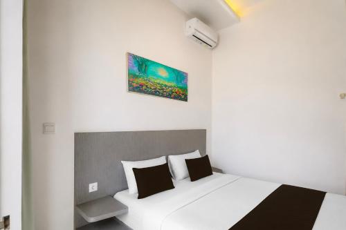 a bedroom with a white bed and a painting on the wall at Townhouse Oak The Vinhill Studio in Bangli