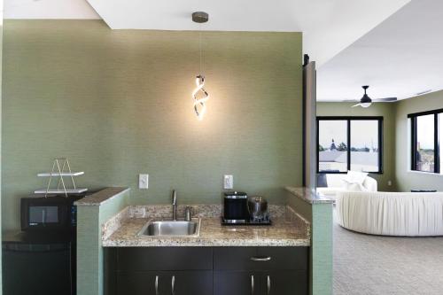 a kitchen with a sink and a living room at The Strathallan Rochester Hotel & Spa, Tapestry by Hilton in Rochester