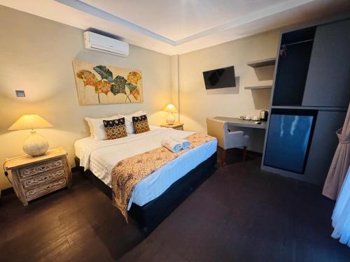 a bedroom with a bed and a desk and a television at The Lodge Canggu in Tumbak Bayuh