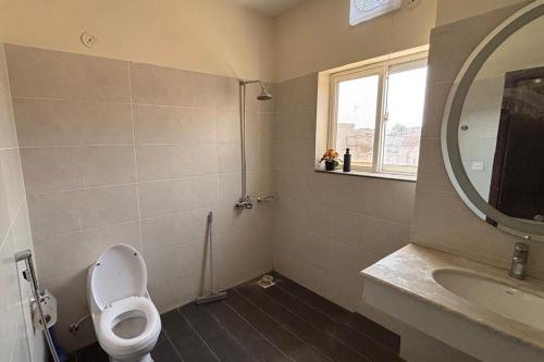 a bathroom with a toilet and a sink and a mirror at Spacious Apartment by Urban Residence in Multan