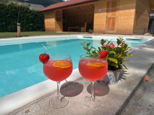 two cocktails in glasses next to a swimming pool at Apartment in St Michael near Ski Slopes in Sankt Michael im Lungau