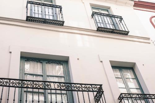 un edificio blanco con balcones negros. en Casa Boutique La Pila del Pato, en Sevilla