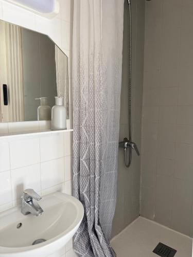 a bathroom with a sink and a shower curtain at Hotel le Bon Soleil in Les Sables-d'Olonne
