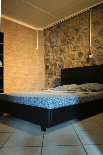 a bed in a room with a stone wall at Bungalow Le Cocotier in Sainte-Rose