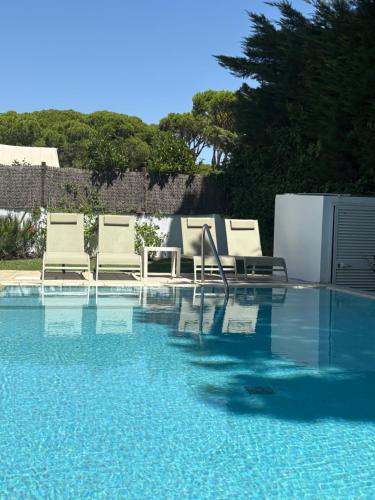 a swimming pool with chairs and a table and water at Villa Pinares de Roche - Piscina privada - Playa a 6 min in Roche