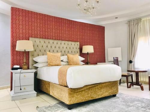 a bedroom with a large bed with a red wall at Radiant Resort in Manzini