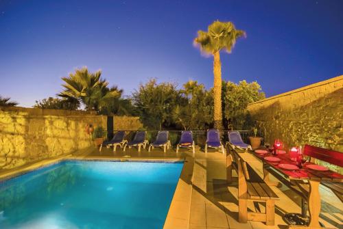 a swimming pool with lounge chairs and a palm tree at Strawberry Hills in Żejtun