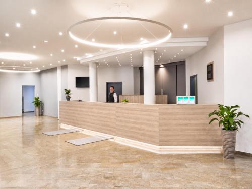 a woman standing at a reception desk in a lobby at Sunday Hotel Stuttgart Herrenberg in Herrenberg