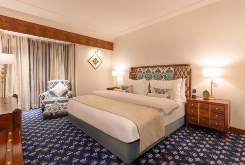 a hotel room with a large bed and a chair at Faisalabad Serena Hotel in Faisalabad