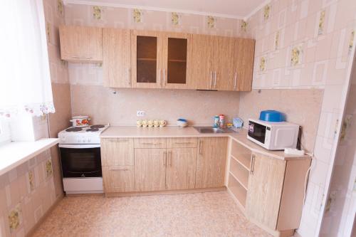 a small kitchen with wooden cabinets and a microwave at Apartment on Sverdlova in Tyumen