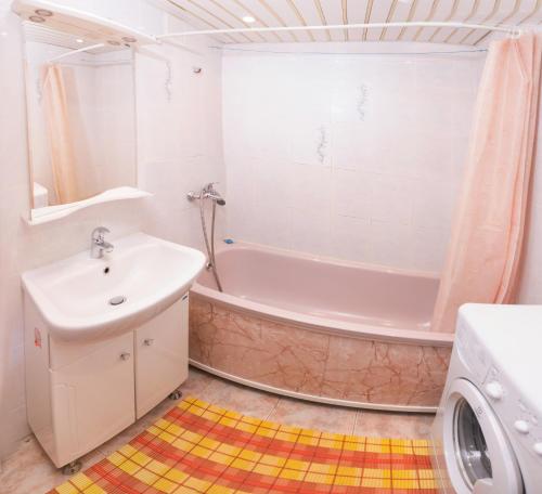 a bathroom with a tub and a sink and a washing machine at Apartment on Sverdlova in Tyumen