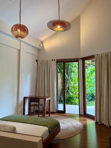 a bedroom with a bed and a table and windows at SEACLUB Siargao in General Luna