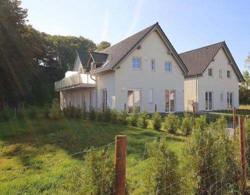 a white house with a fence in a yard at Haus Sonne - Whg 08 in Thiessow