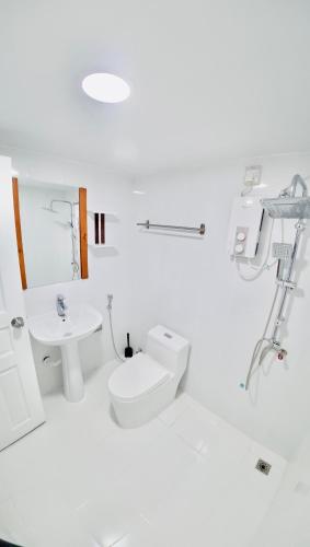 a white bathroom with a toilet and a sink at VelaaOlhu - Turtle Hive Thulusdhoo in Thulusdhoo
