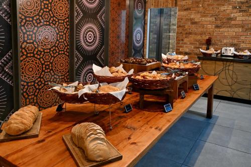 a table with several baskets of bread and pastries at Fountains Hotel by Neighbourgood in Cape Town