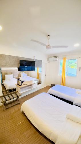 a hotel room with two beds and a tv at VelaaOlhu - Turtle Hive Thulusdhoo in Thulusdhoo