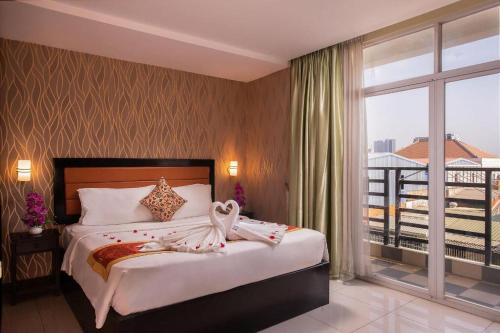 a bedroom with a large bed and a balcony at Wind Holiday Hotel in Phnom Penh