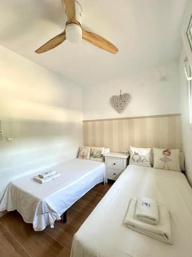a bedroom with two beds and a ceiling fan at Villa El Carmen in Sanlúcar la Mayor