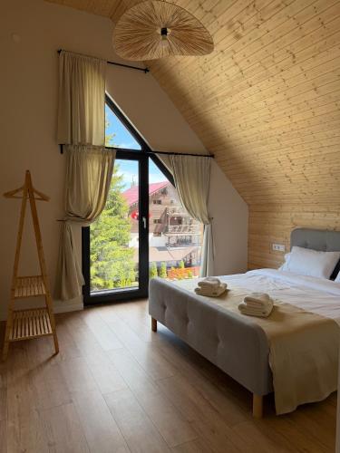 a bedroom with a large bed and a large window at Cabana Nord Side in Muntele Cacovei