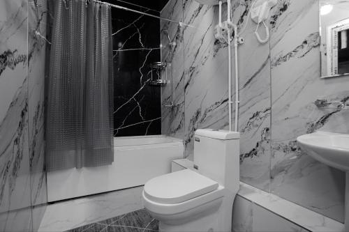 a black and white bathroom with a toilet and a sink at Family Hotel in Khujand
