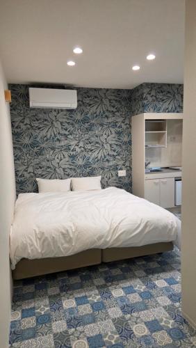 a bedroom with a bed with a wall at ガジュマル House in Tonosho