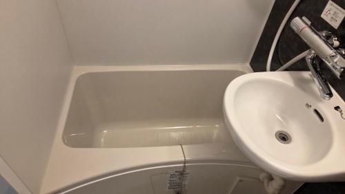 a bathroom with a sink and a bath tub at ガジュマル House in Tonosho