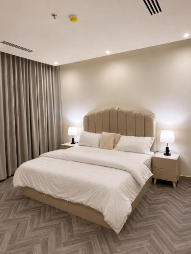 a bedroom with a large white bed with two lamps at ڤيا Via in Buraydah