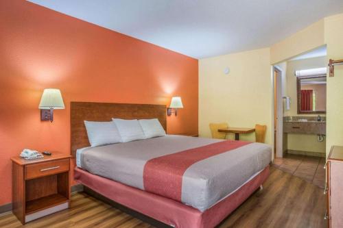a hotel room with a large bed with an orange wall at Rodeway Inn & Suites in Lakeview