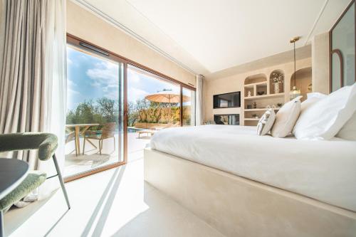 a bedroom with a large bed and a large window at La Bastide des Rameaux - Boutique Hôtel & Spa in Callas