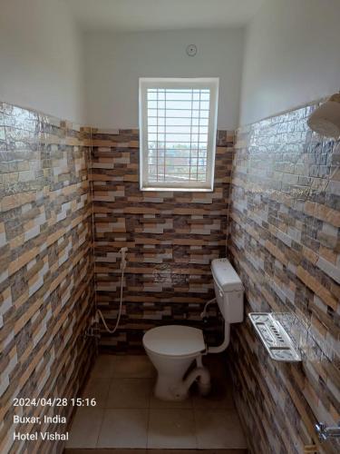 a bathroom with a toilet and a window at Hotel Vishal in Buxar