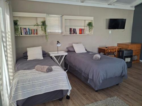 a bedroom with two beds and a tv and a table at Myplekki in Bethlehem