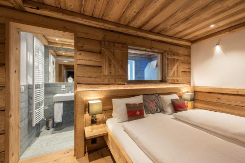 a bedroom with wooden walls and a bed with a window at Hotel Crusch Alba Zernez in Zernez