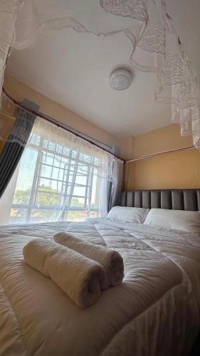 a towel laying on a bed in front of a window at Lucci suites in Kisumu