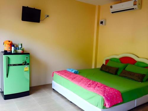 a bedroom with a green bed and a refrigerator at MAIYOK in Ko Si Chang