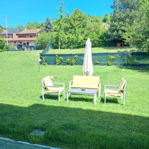 a lawn with two chairs and an umbrella and a table at TerrazzaPonente in Monte San Pietro
