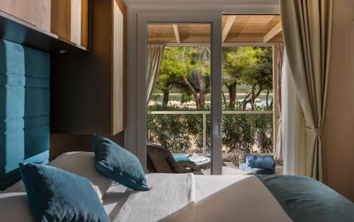 a bedroom with a bed and a large window at Mobile Homes Lopari in Nerezine