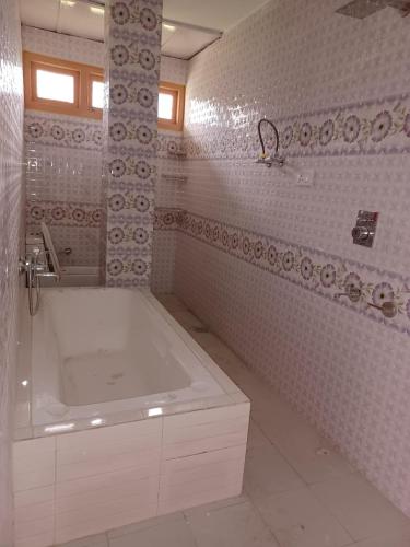 a white bathroom with a tub and a sink at DELTA Inn HOMESTAY in Khashdhār